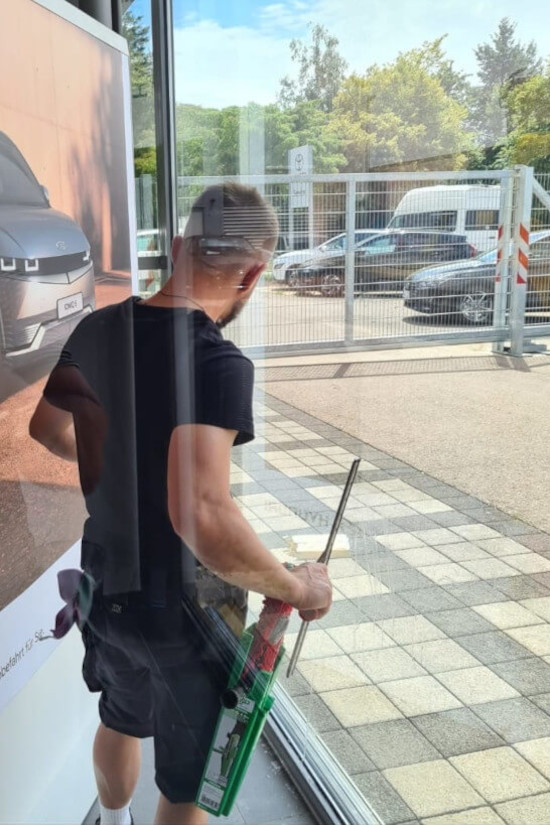 Ein Fensterreiniger reinigt gerade eine Glasscheibe bzw. ein Fenster